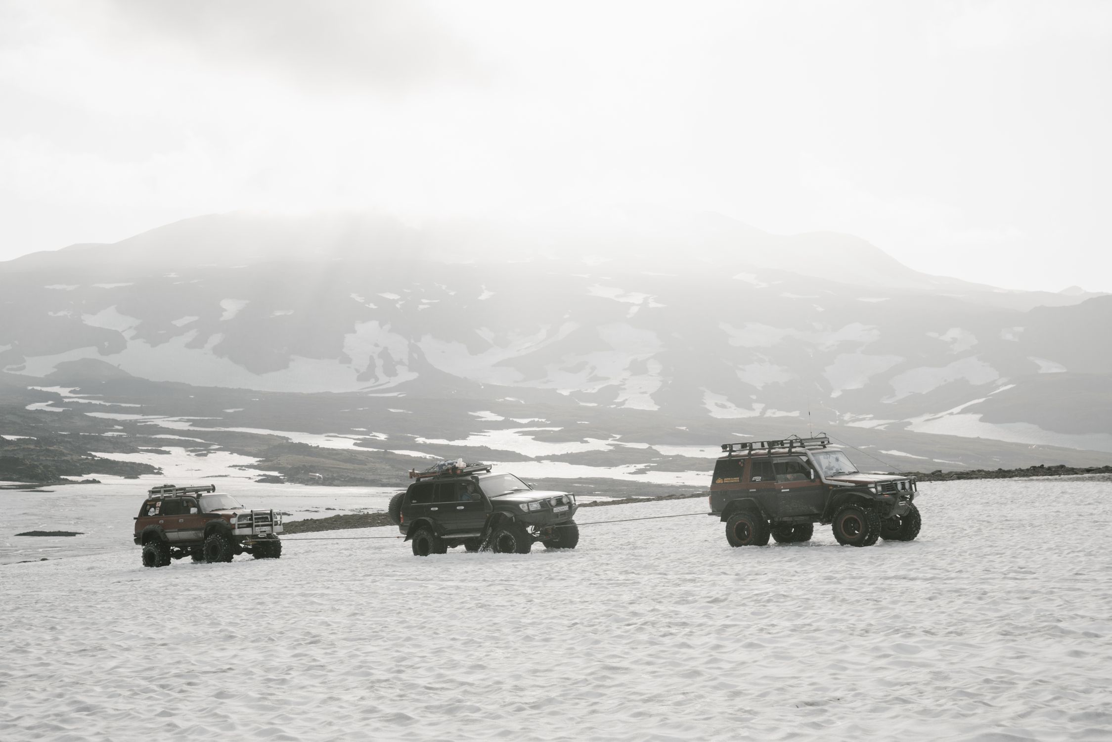 Four SUVs on a snowy mountain landscape, perfect for adventure travel themes.