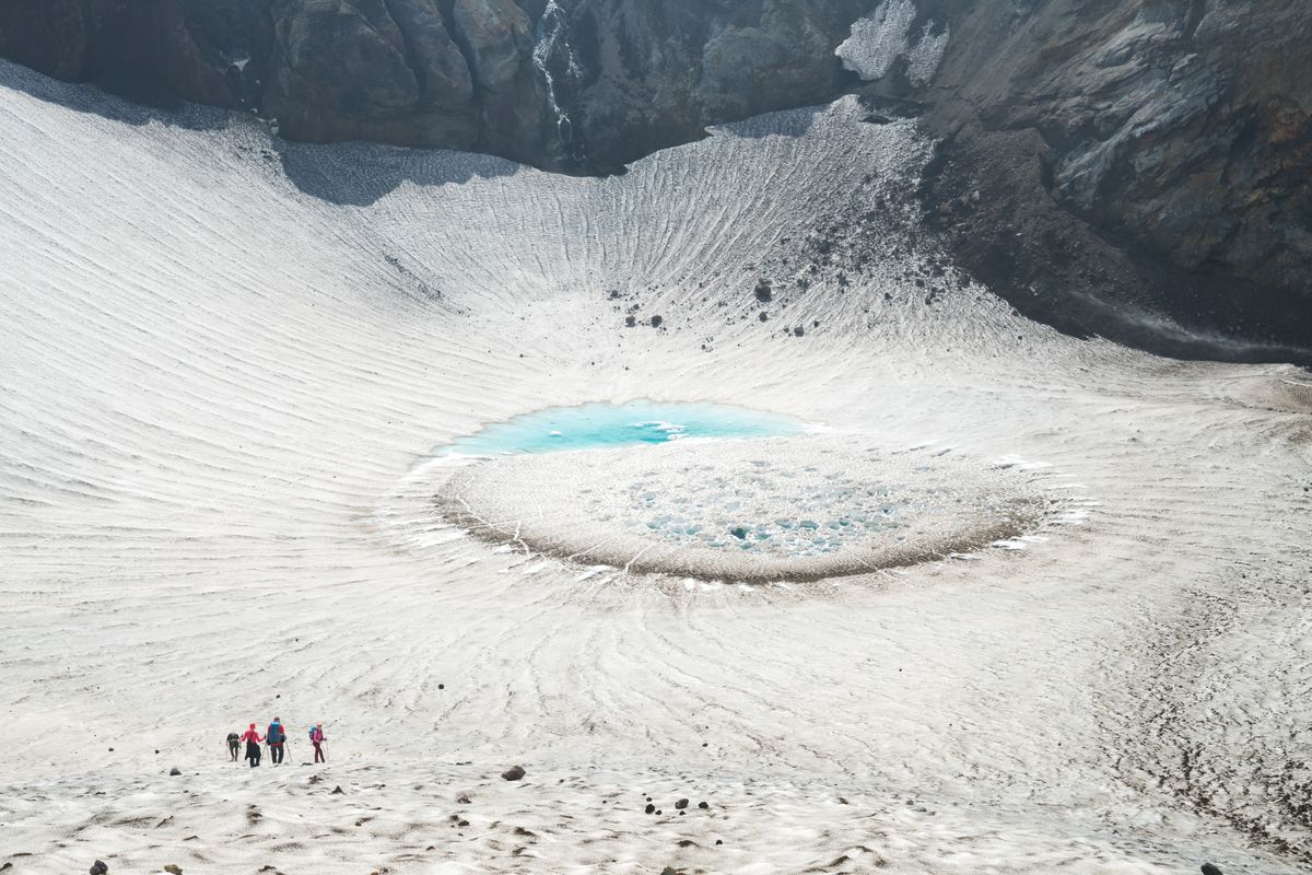a jagged volcanic crater lake surrounded by snow