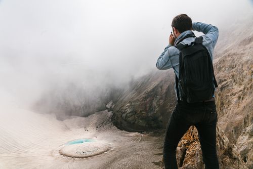 Free Man photographing a foggy mountain crater with a lake in the background. Stock Photo