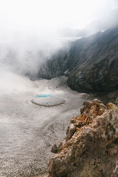 Free Aerial view of a misty crater lake surrounded by rocky mountains, creating a serene natural scene. Stock Photo