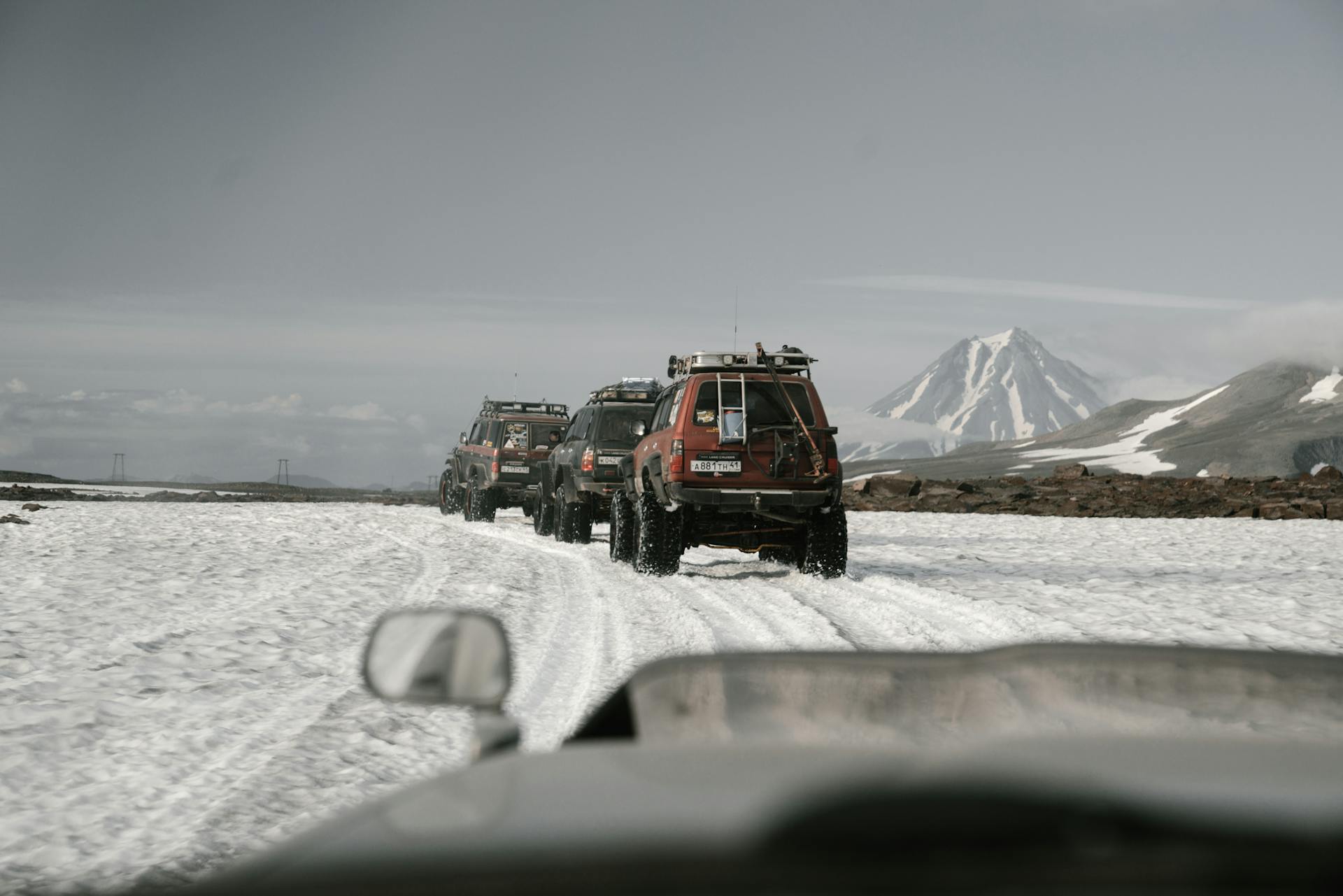 A convoy of jeeps driving through snowy mountain terrains showcasing off-road adventure.
