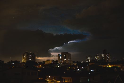 深色厚云漂浮在夜空，建筑物明亮
