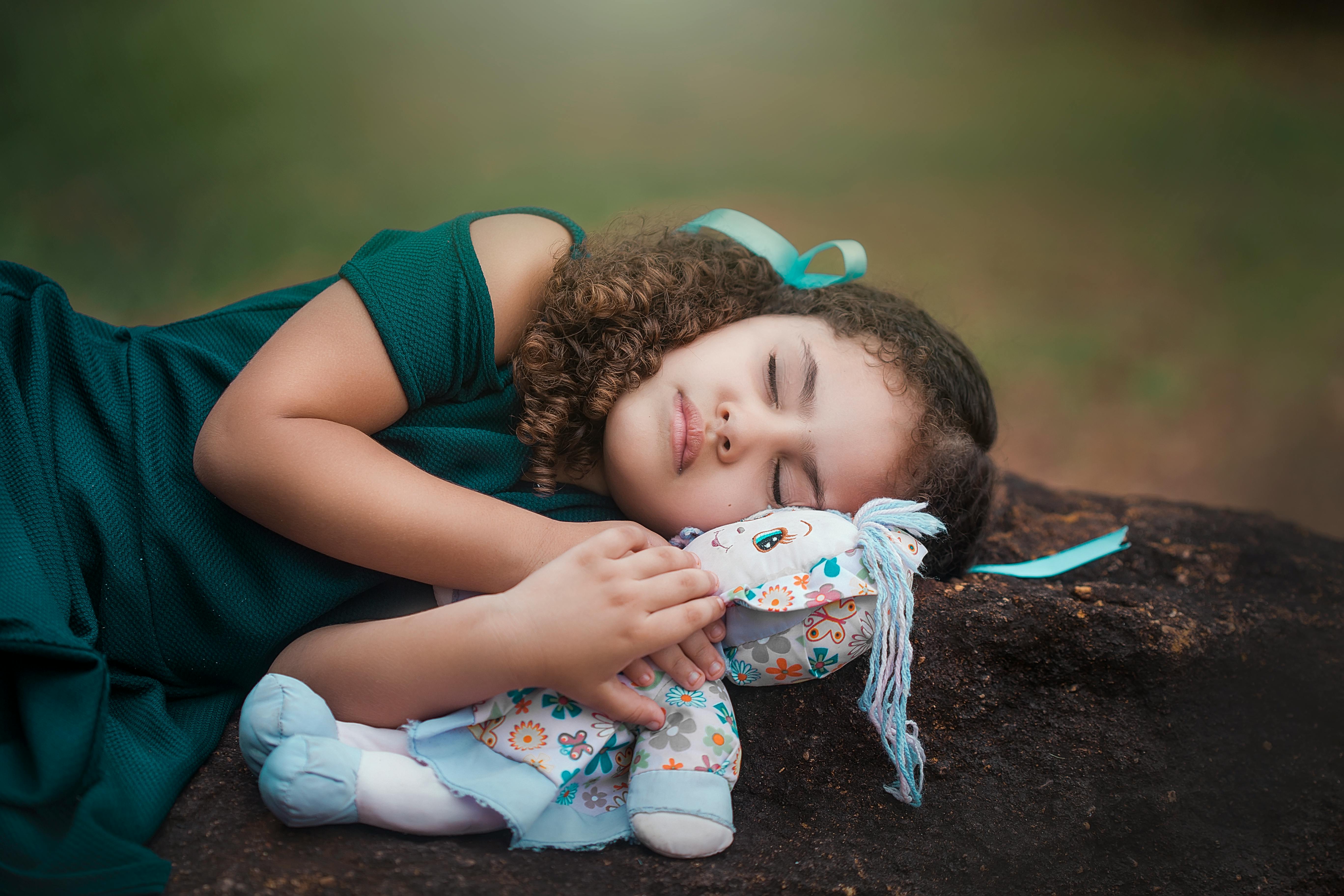 cute ethnic child sleeping on ground with doll