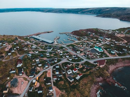 Free Drone view of coastal settlement located between rippling lake and foamy ocean on cloudy day Stock Photo