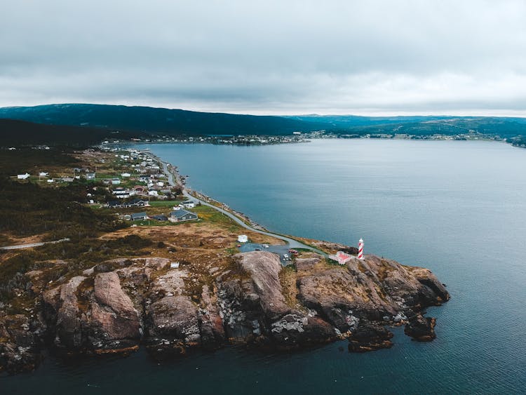 Lighthouse And Residential Buildings On Mount Near Ocean