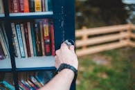 Crop person opening public bookcase in park