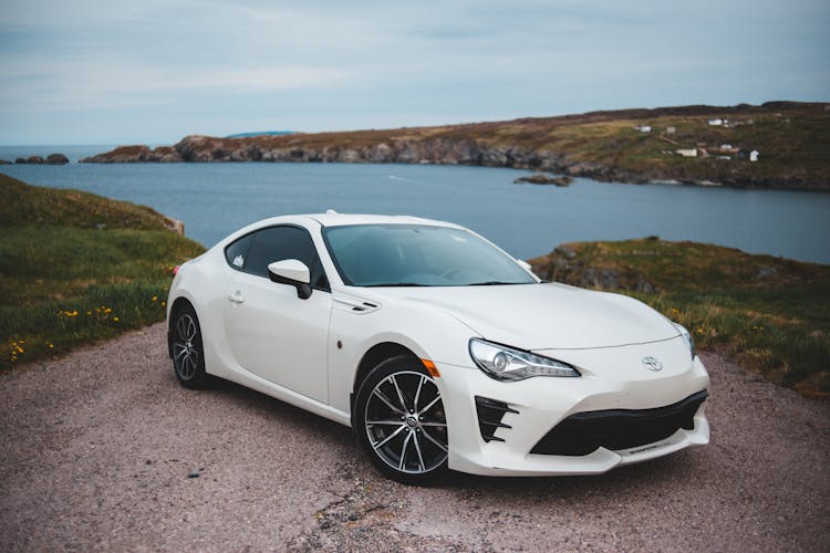 Modern White Car Parked On Picturesque Lake Shore