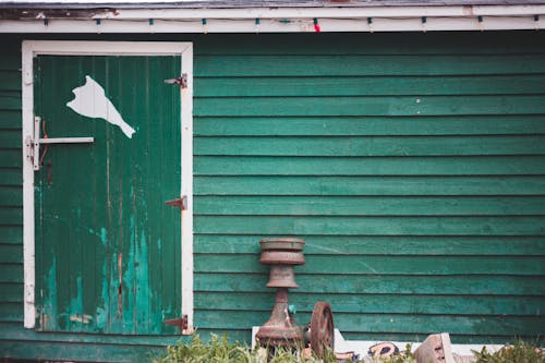 Facade of old green wooden house with shabby door located in countryside in daytime