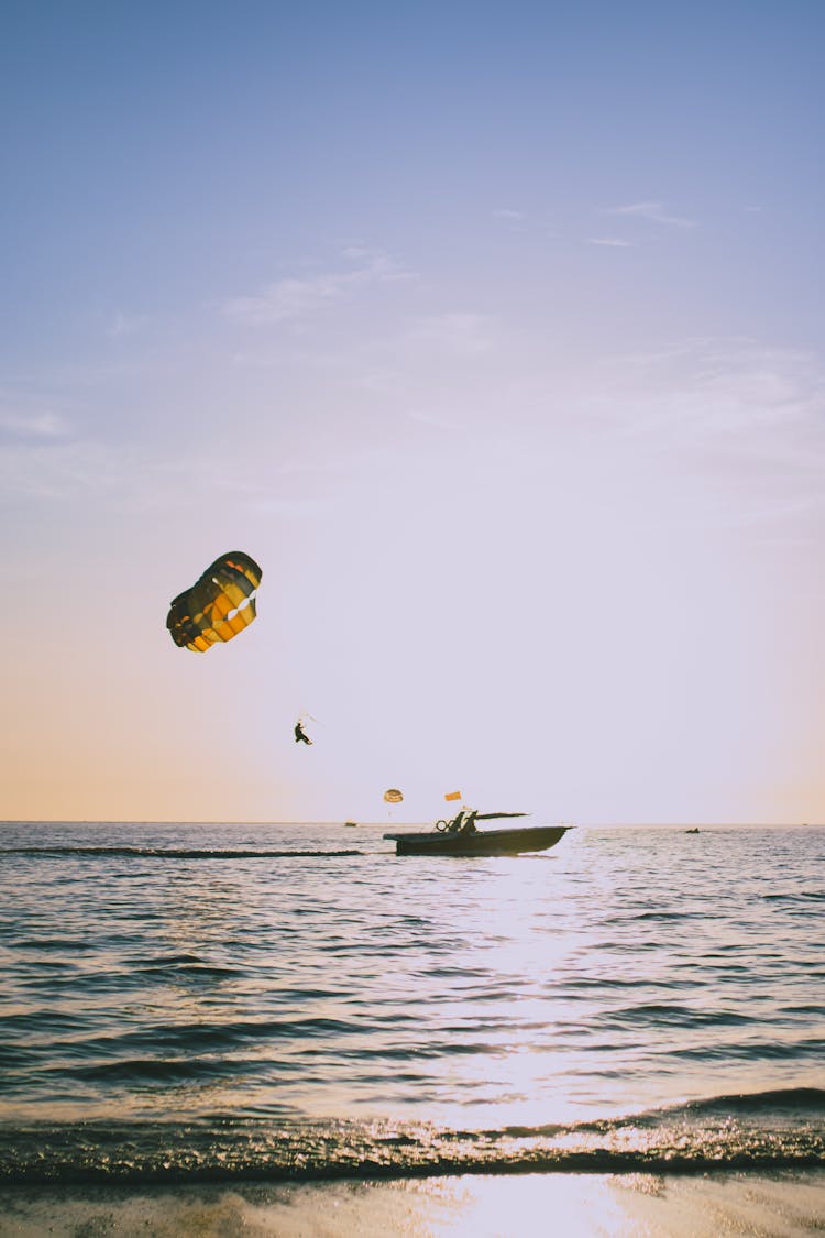 Anonymous Person With Parachute During Parasailing In Sea