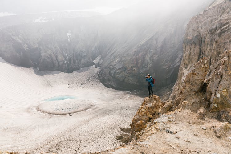 Man Photographing A Small Lake In A Mountain Valley