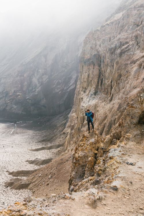 Free Photographer capturing stunning coastal views from a rocky cliff edge. Stock Photo