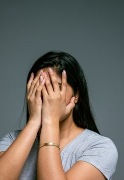 一名女子在工作室里用手捂住脸，显得悲伤又压抑