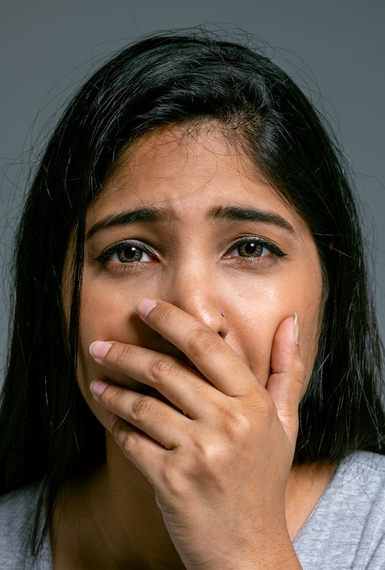 Close-up Portrait Of Terrified Woman Covering Mouth With Hand