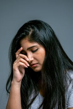 工作室里，一位留着深色长发的女人沉思着摆出姿势，神情若有所思，传达出一种内省的情绪