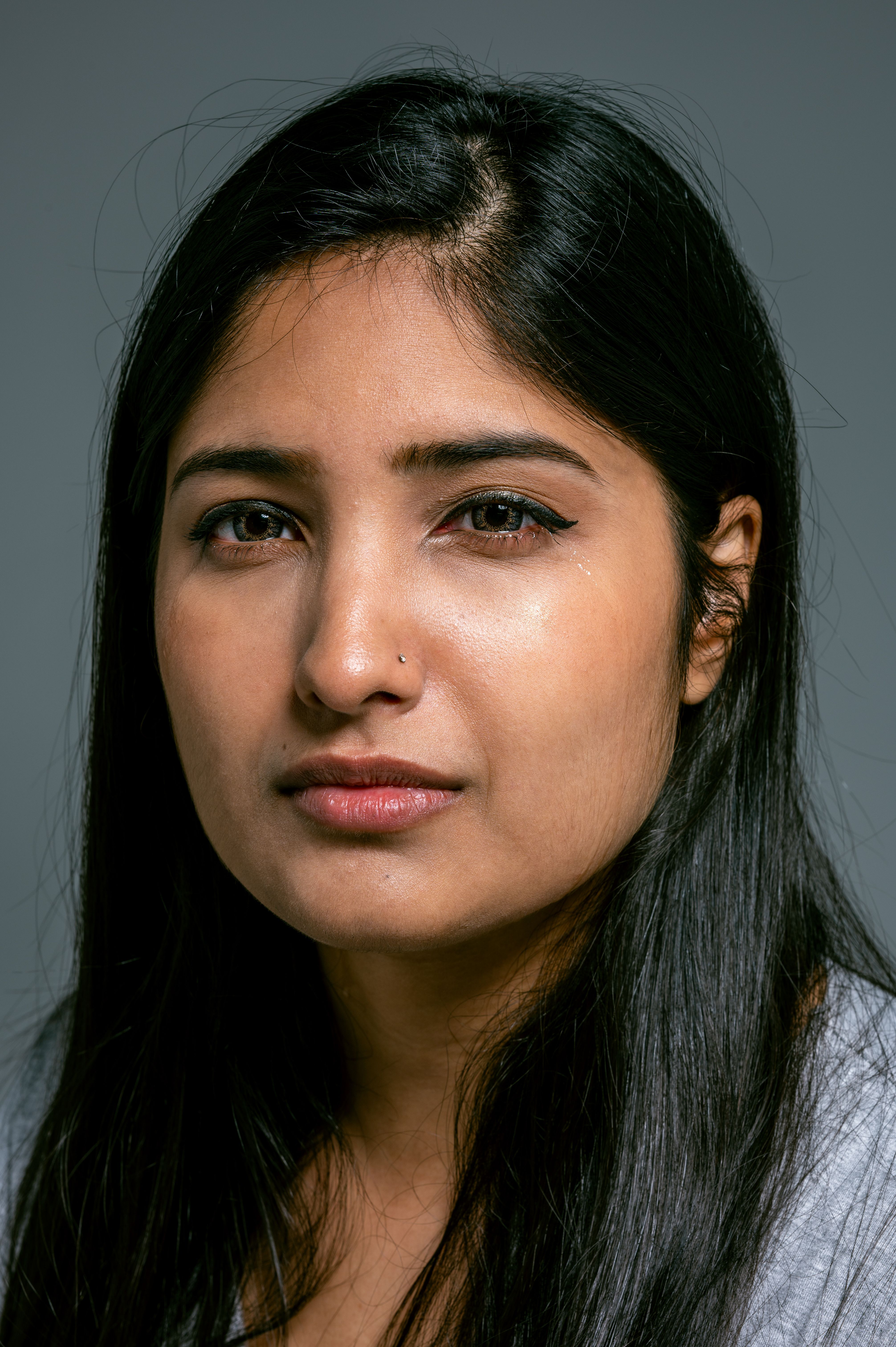 Close-up portrait of a woman with a thoughtful expression in a studio setting.
