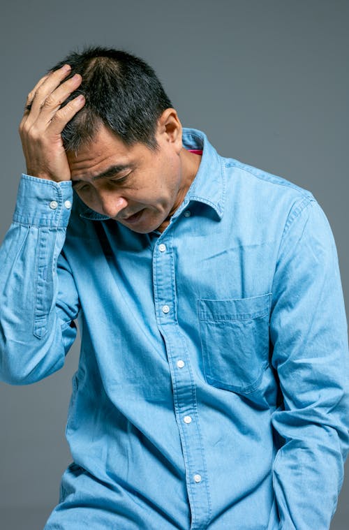 Free Man in Blue Denim Button Up Long Sleeve Shirt Looking Down Stock Photo