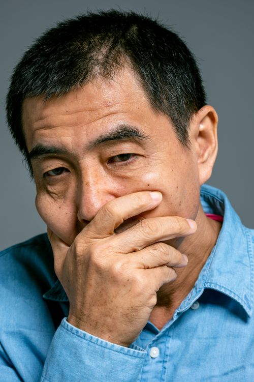 Free Close-up of a man in a blue shirt, hand on mouth, expressing worry and contemplation. Stock Photo