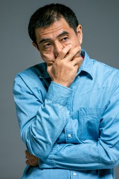 一个穿着蓝色牛仔衬衫的男子陷入沉思的特写，传达出内省的情绪