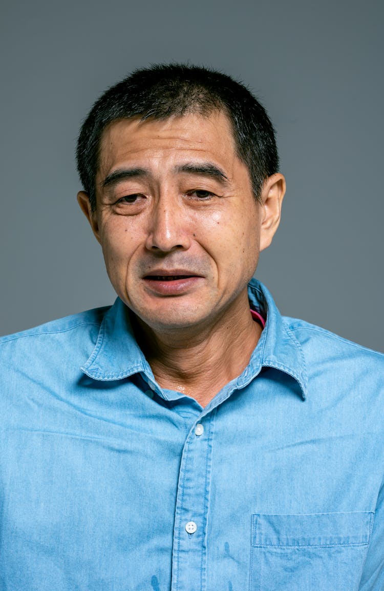 Man In Blue Button Up Shirt With A Worried Face