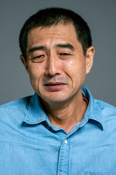 一位身穿蓝色牛仔衬衫的男子，在特写肖像中流露出深思熟虑的情感