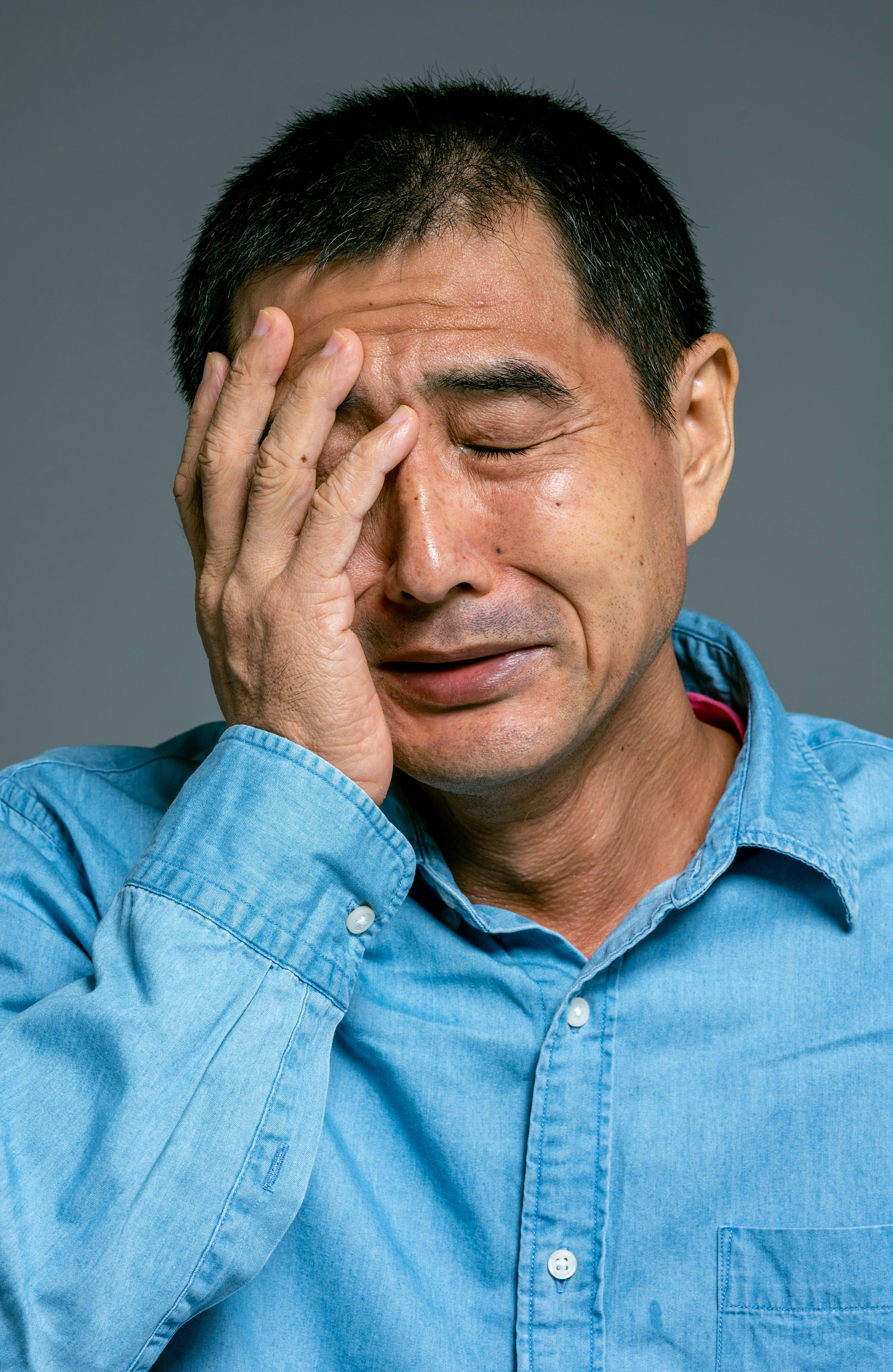 an emotional man in blue denim button up shirt