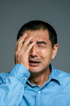 特写镜头中，一个穿着蓝色衬衫的人闭着眼睛，流露出情绪