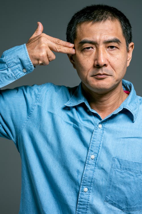 Man in Blue Top Pointing Fingers on His Head