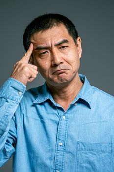 特写镜头中，一个穿着蓝色牛仔衬衫的成年男子正在深思