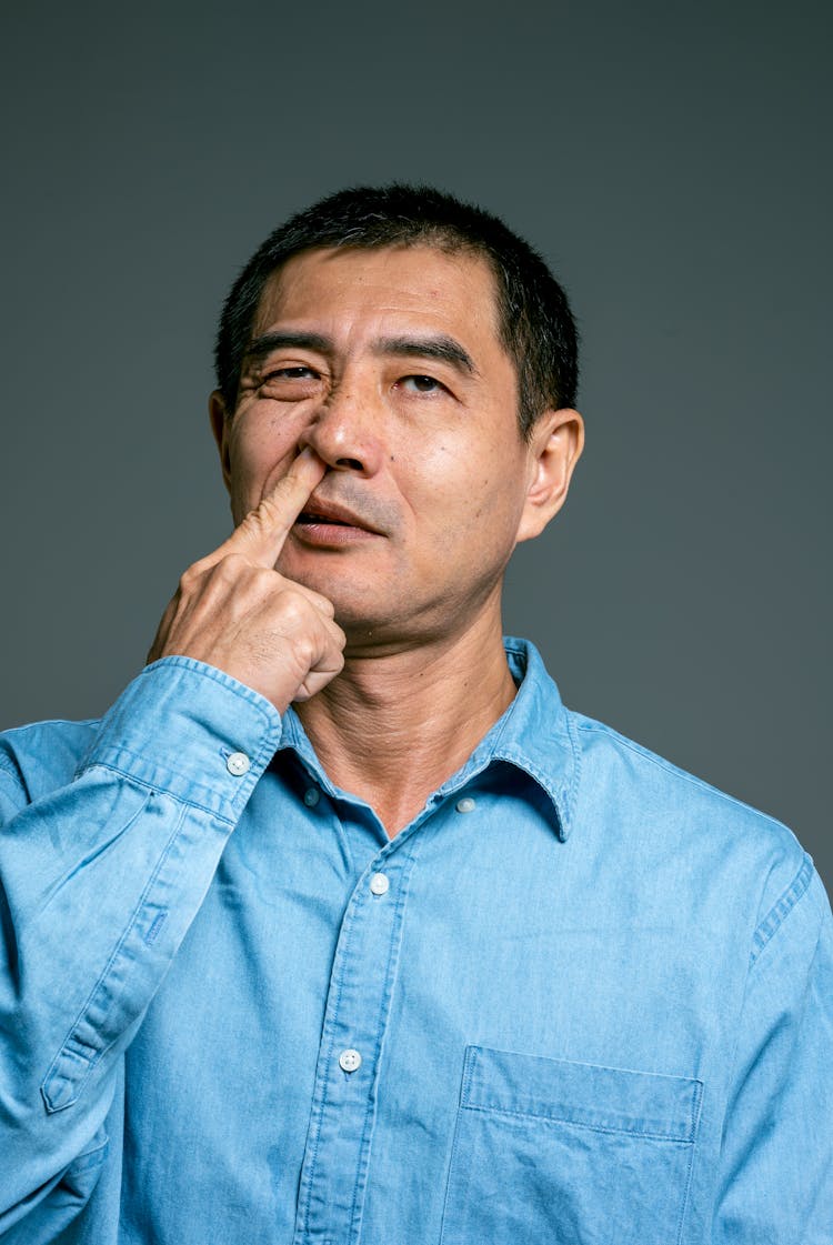 Man In Blue Top Picking Nose