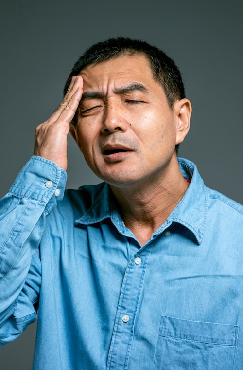 Man in Blue Denim Button Up Shirt With Headache