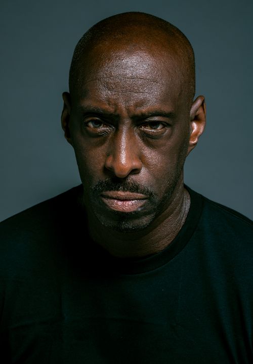Free Close-up portrait of a serious bald man wearing a black shirt against a dark background. Stock Photo