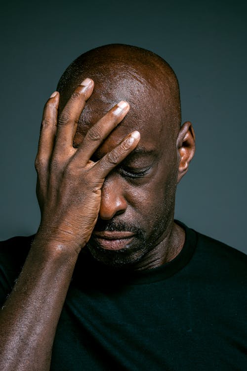 Man in Black Crew Neck Shirt Covering His Face