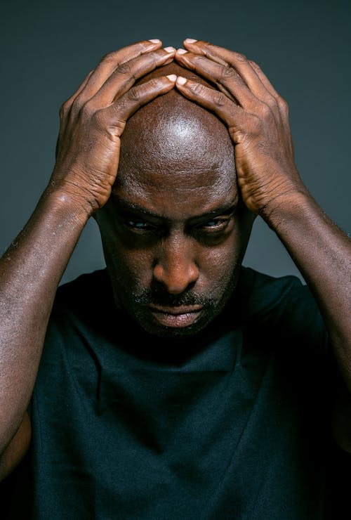 Man in Blue Crew Neck Shirt Holding His Head With Both Hands