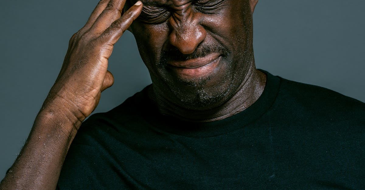 An adult man in distress with his hand on his head, expressing pain or frustration.