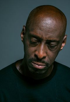 一位秃头男子闭着眼睛，表情严肃的特写肖像