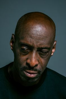 一个秃头、留着小胡子的男子沉思着向下看的特写肖像