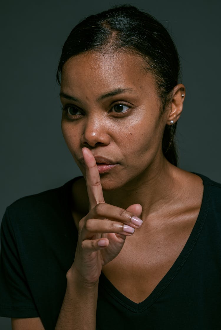 Woman In Black Top With Finger On Lips