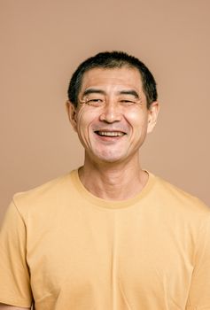 Cheerful middle-aged man wearing a yellow t-shirt, smiling warmly against a neutral backdrop.