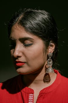 这幅肖像画描绘了一位闭目、佩戴银耳环、身着红衣的女子，画面宁静