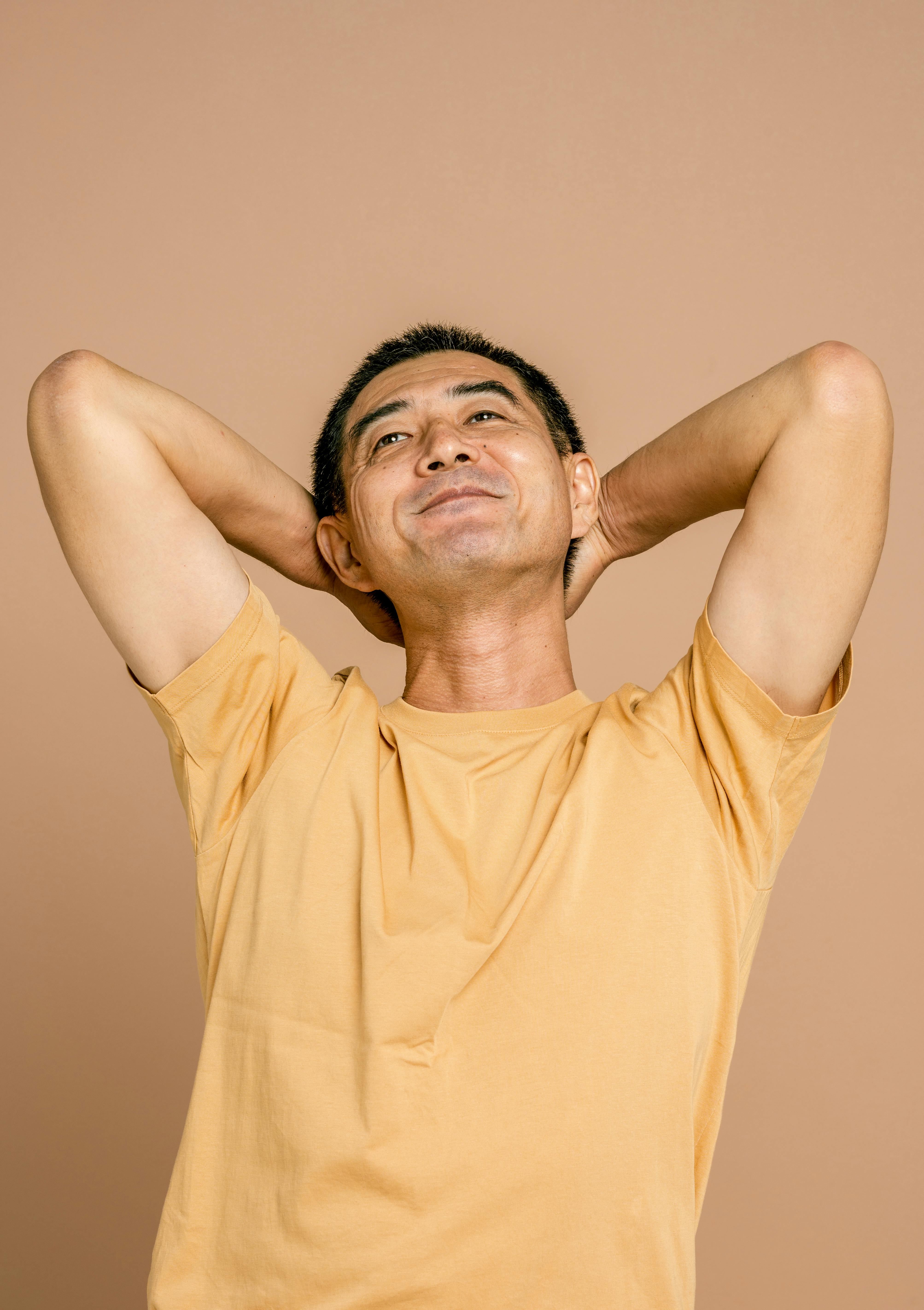 man in yellow crew neck t shirt with hands on head