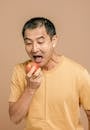 A Man in Yellow Crew Neck T-shirt Holding Red Apple Fruit