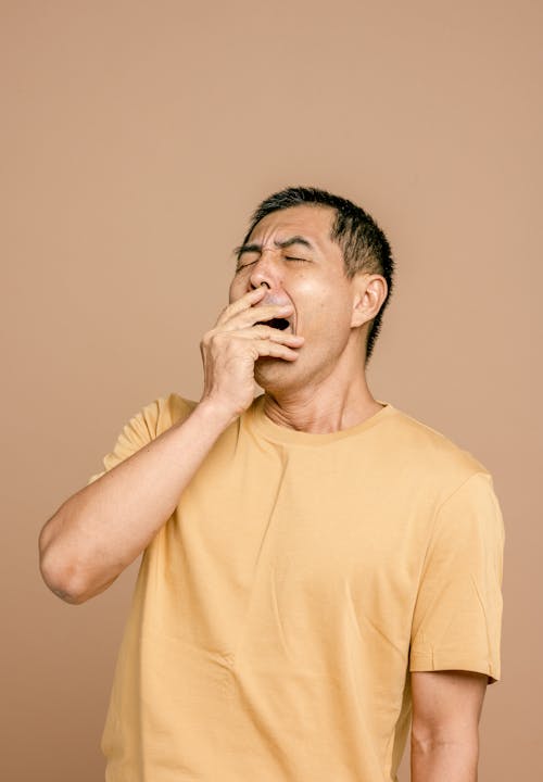 Man in Crew Neck T-shirt Covering His Mouth with Eyes Closed