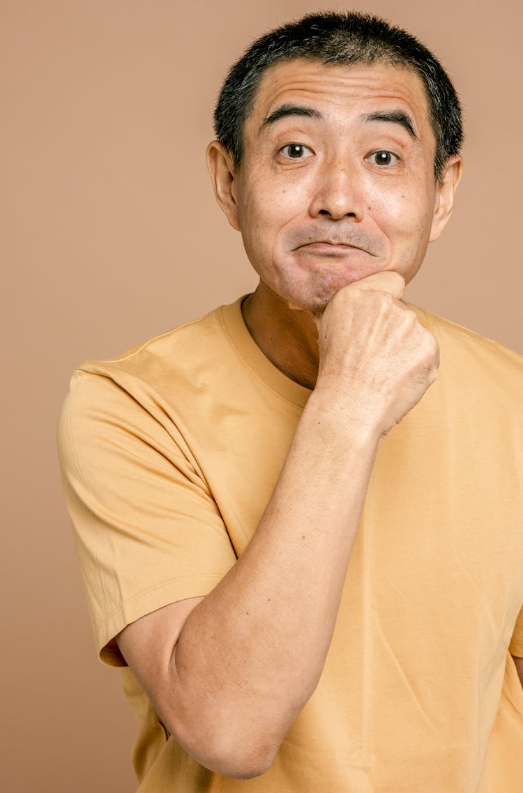 A Man In Yellow Crew Neck T-shirt Flashing A Timid Smile