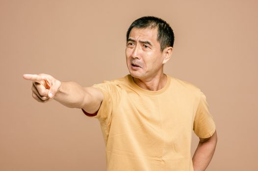 资深亚洲男子在棕色背景下愤怒地指着