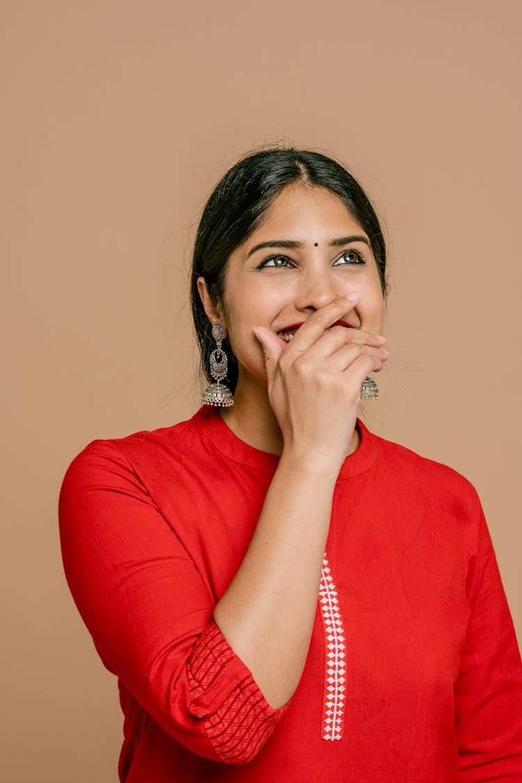 A Woman In Red Dress Covering Her Smile With Her Hand