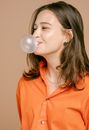 Woman in Orange Button Up Shirt Blowing a Bubble Gum