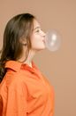 A Woman in Orange Button Up Shirt Blowing a Bubble Gum