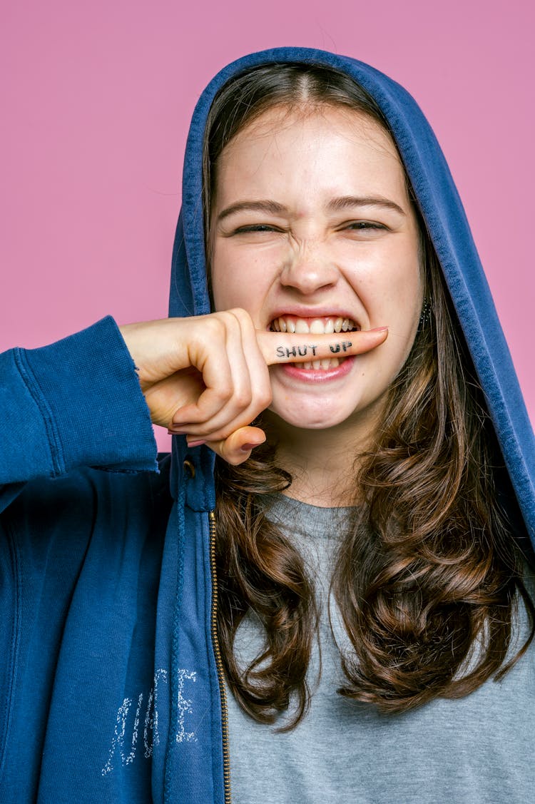 A Young Woman Biting Her Index Finger With A Shut Up Note