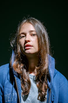 Portrait of a young woman in a blue hoodie under dramatic studio lighting.