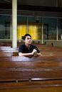一名身穿黑色衬衫的男子双手紧握，在教堂长凳上沉思祈祷